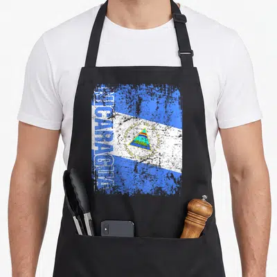 Nicaragua distressed apron - Vertical Nicaragua text and coat of arms on distressed blue white and yellow flag — shown on a black cotton canvas apron against a white background