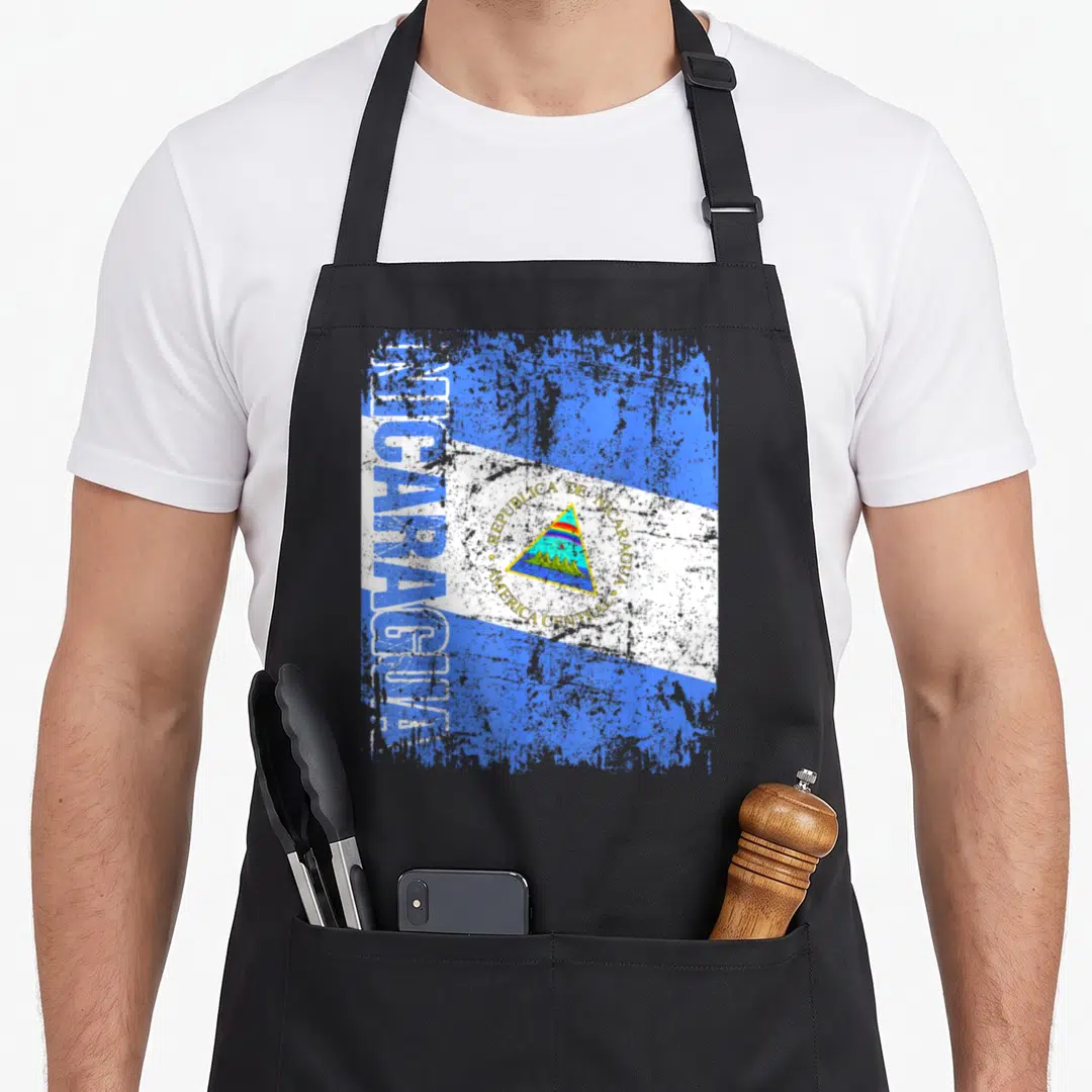 Nicaragua distressed apron - Vertical Nicaragua text and coat of arms on distressed blue white and yellow flag — shown on a black cotton canvas apron against a white background