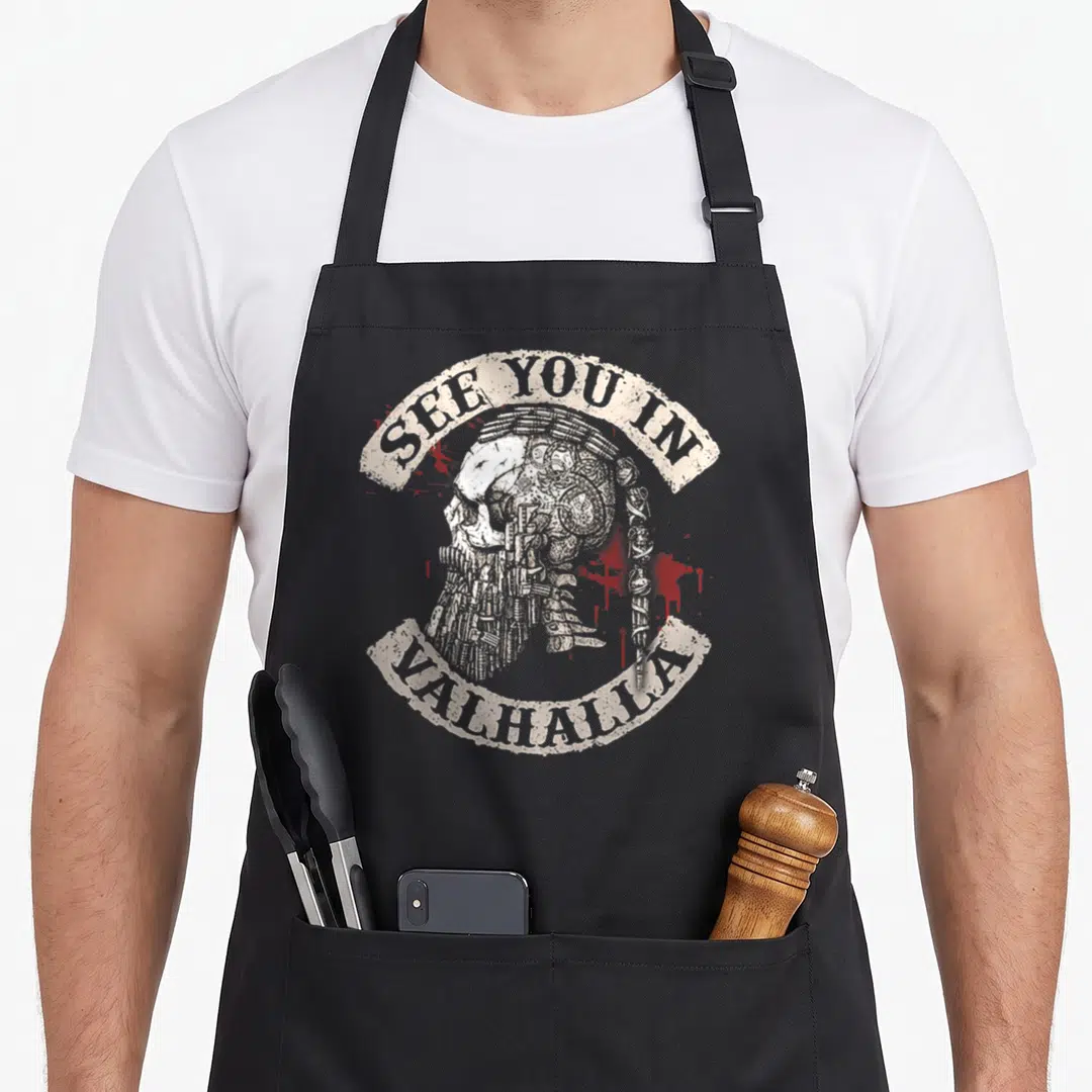 See valhalla viking apron - Distressed skull with braided beard and SEE YOU IN VALHALLA text on black apron — shown on a black cotton canvas apron against a white background