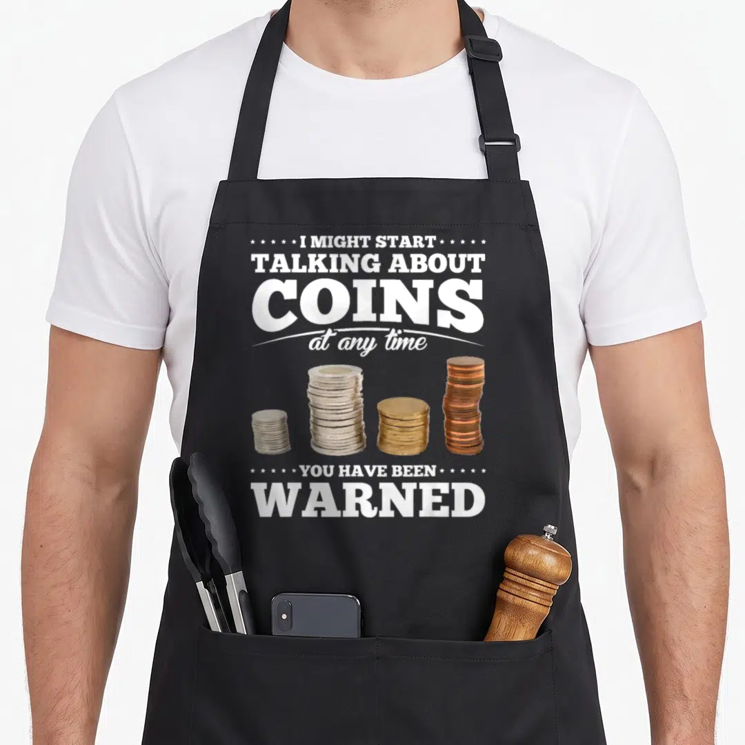 Coin collecting apron - I might start talking about coins text above four stacks of silver gold and copper coins — shown on a black cotton canvas apron against a white background