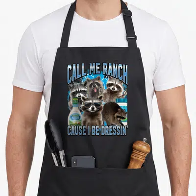 Ranch meme apron - Four raccoons and two ranch dressing bottles on blue lightning with text — shown on a black cotton canvas apron against a white background
