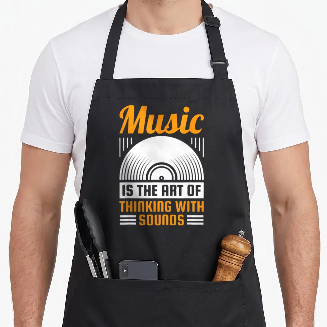 Thinking sound of music apron - Orange Music text above white vinyl record and stacked quote about sounds — shown on a black cotton canvas apron against a white background