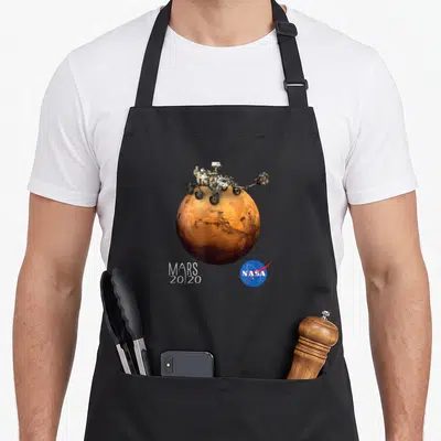 Rover nasa apron - Mars rover perched on orange planet with MARS 20/20 text and blue NASA logo — shown on a black cotton canvas apron against a white background