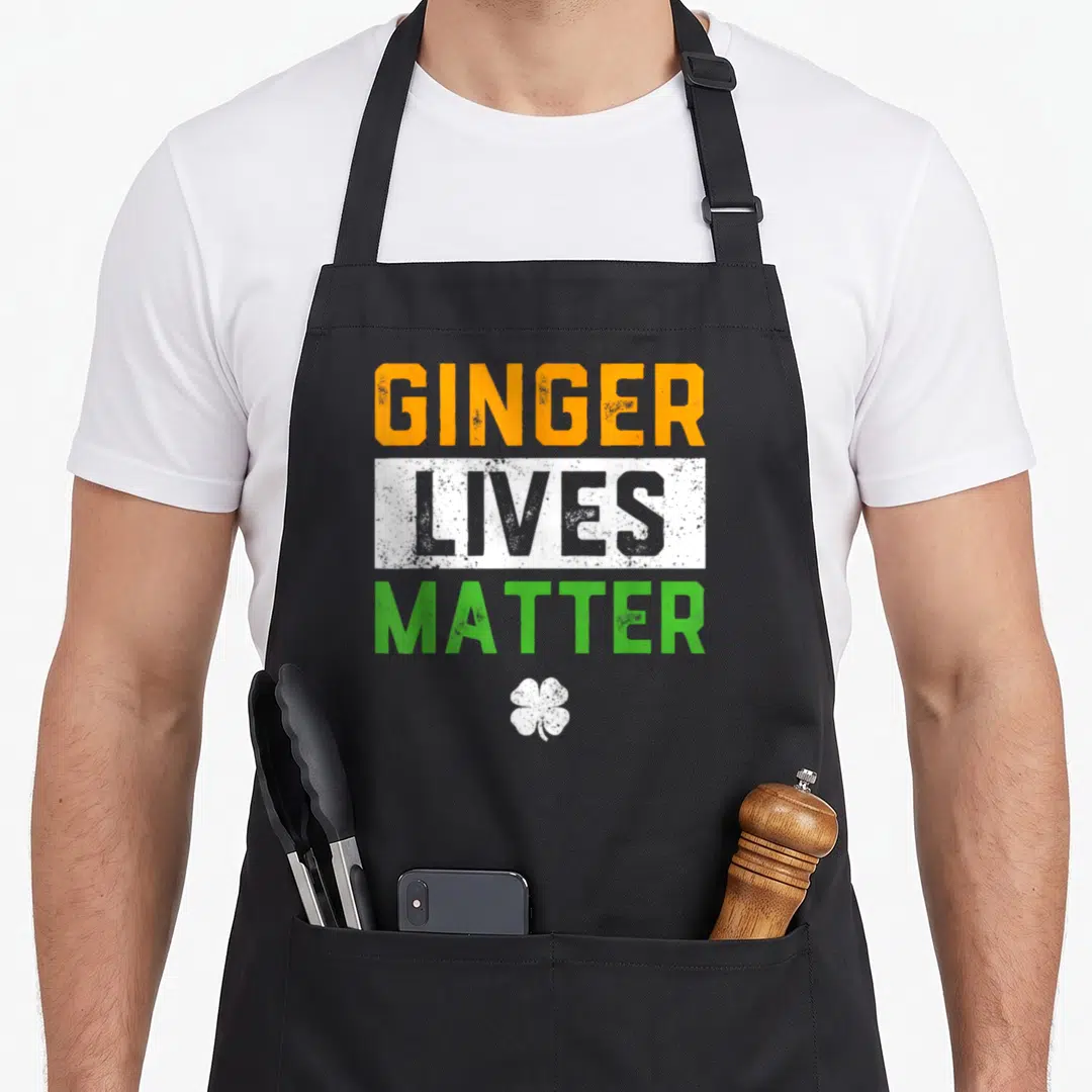 Live st patrick day aprons - Stacked GINGER LIVES MATTER text in orange grey green with white four leaf clover on grey — shown on a black cotton canvas apron against a white background
