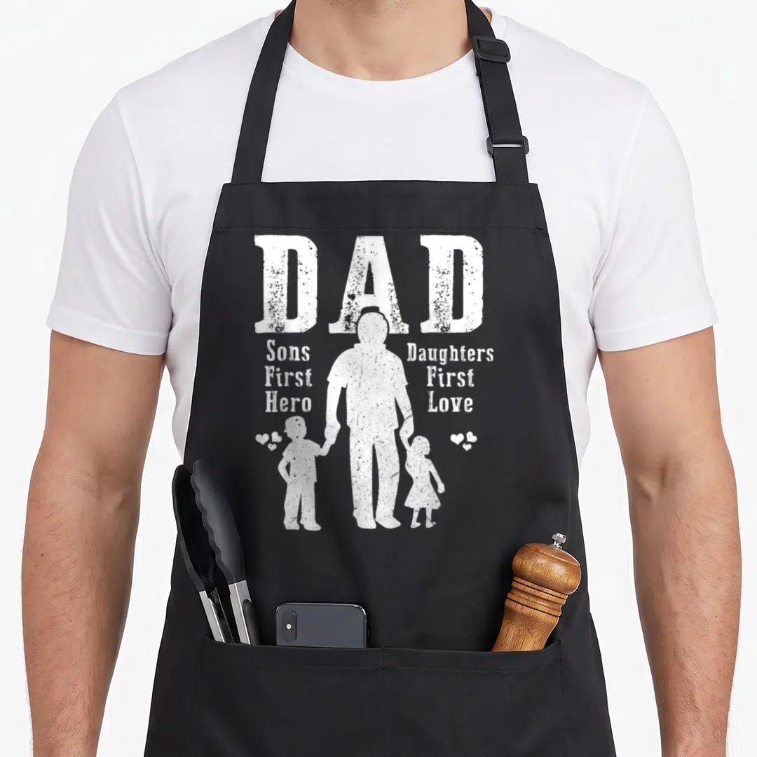 Son grill daddy apron - White distressed DAD text with father silhouette holding hands with son and daughter — shown on a black cotton canvas apron against a white background