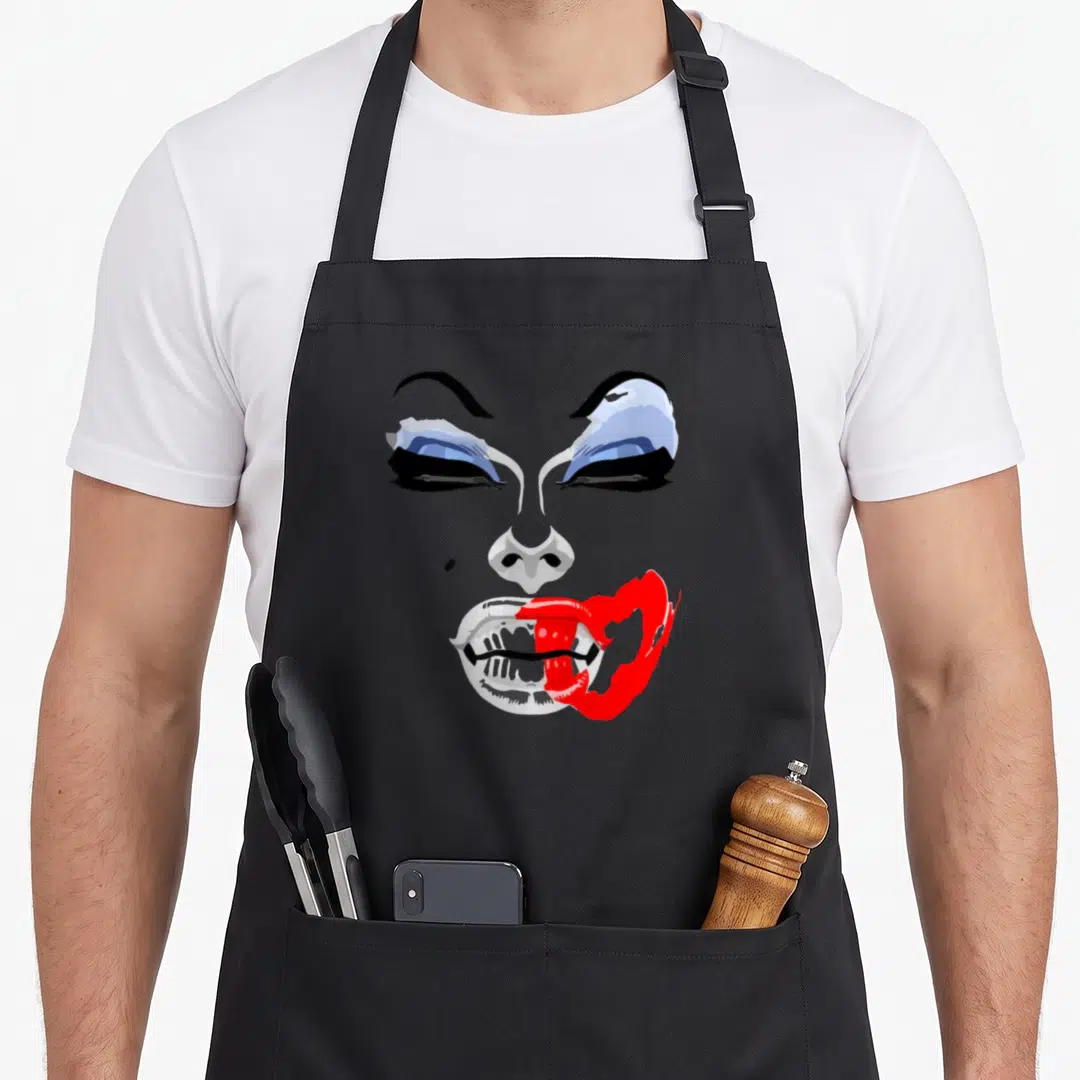 Alaskas makeup apron - Minimalist face with blue eyes and bright red lips on black background — shown on a black cotton canvas apron against a white background