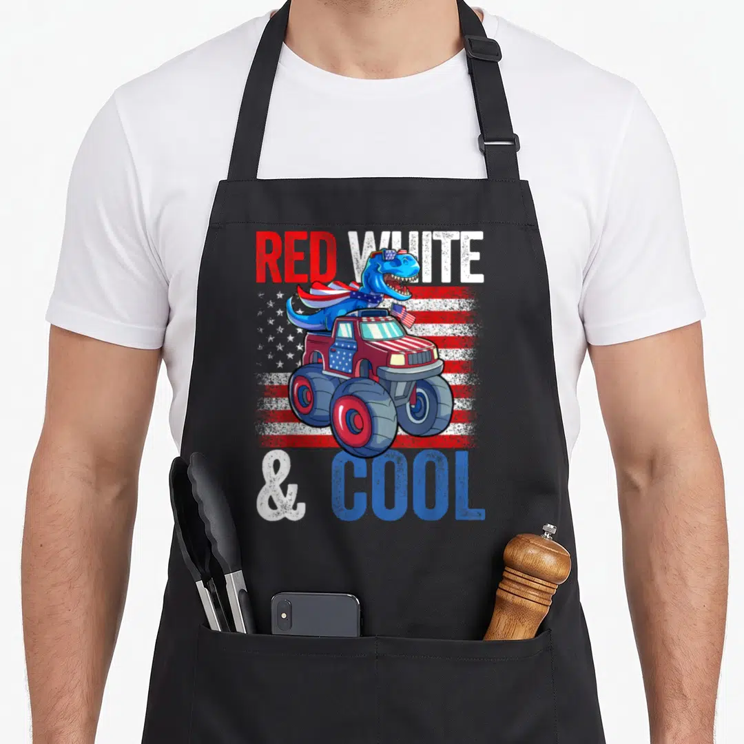 Dinosaur monster 4th of july apron - Blue dinosaur in monster truck over distressed red white blue flag with text — shown on a black cotton canvas apron against a white background