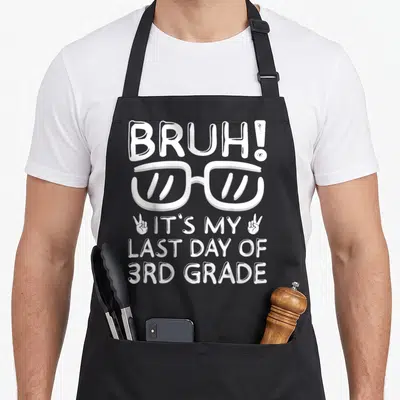 3rd bruh grade apron - White BRUH text, glasses, and peace sign hands printed on black bib — shown on a black cotton canvas apron against a white background