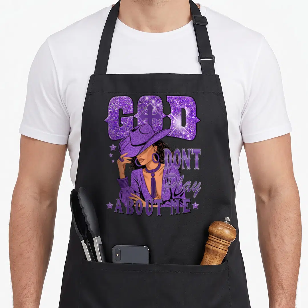 God african american aprons - Purple cowgirl illustration with text GOD DON'T Play ABOUT ME and stars on black fabric — shown on a black cotton canvas apron against a white background