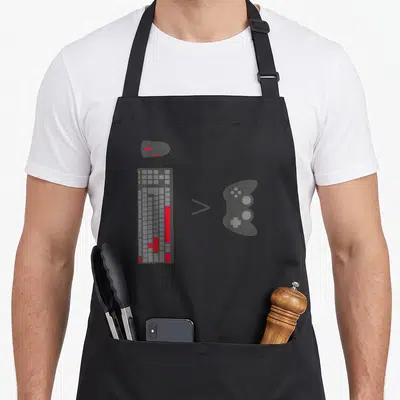 Console gaming apron - Grey keyboard mouse and controller with greater than symbol in minimalist style — shown on a black cotton canvas apron against a white background