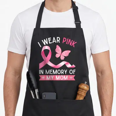 Funny memory breast cancer awareness aprons - I WEAR PINK IN MEMORY OF MY MOM ribbon butterfly text design — shown on a black cotton canvas apron against a white background