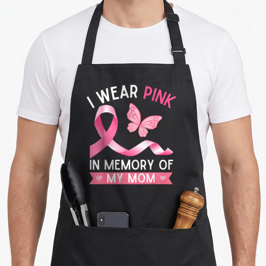 Funny memory breast cancer awareness aprons - I WEAR PINK IN MEMORY OF MY MOM ribbon butterfly text design — shown on a black cotton canvas apron against a white background
