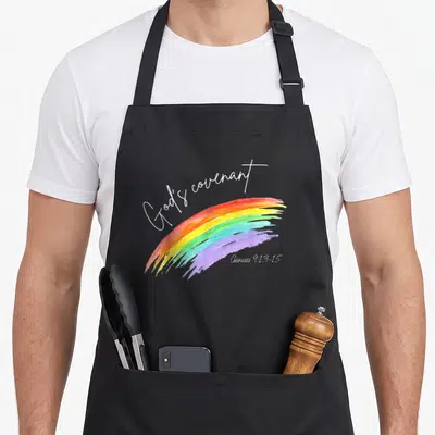 God rainbow apron - Watercolor rainbow in red orange yellow green blue purple white with Genesis 9:13-15 text — shown on a black cotton canvas apron against a white background