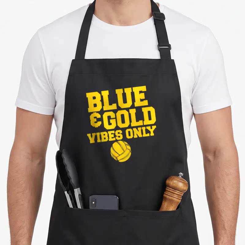 Blue school game aprons - YELLOW stacked text BLUE, & GOLD, VIBES ONLY above a yellow volleyball illustration — shown on a black cotton canvas apron against a white background