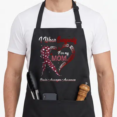 Brain aneurysm awareness ribbon apron - I Wear Burgundy For My Mom ribbon heart awareness typography design — shown on a black cotton canvas apron against a white background