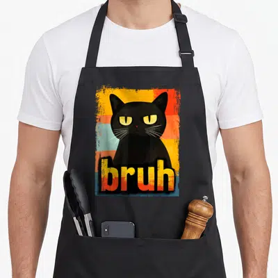 Bruh cat apron - Grumpy black cat illustration with bruh text on distressed multicolored stripes — shown on a black cotton canvas apron against a white background