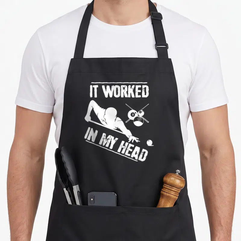 Worked billiards apron - Distressed white text IT WORKED IN MY HEAD above billiard player silhouette and numbered balls — shown on a black cotton canvas apron against a white background