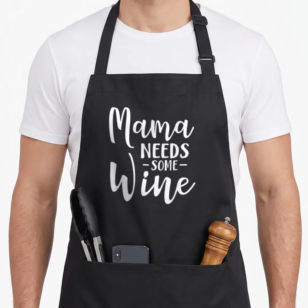 Mama wine aprons - White stacked typography reading Mama NEEDS some Wine on black fabric — shown on a black cotton canvas apron against a white background