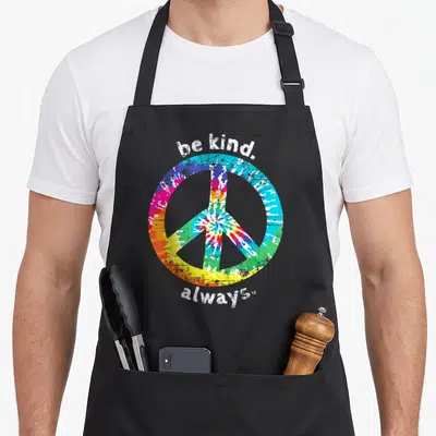 Alway tie-dye apron - Tie-dye peace symbol with be kind always text in white distressed font — shown on a black cotton canvas apron against a white background