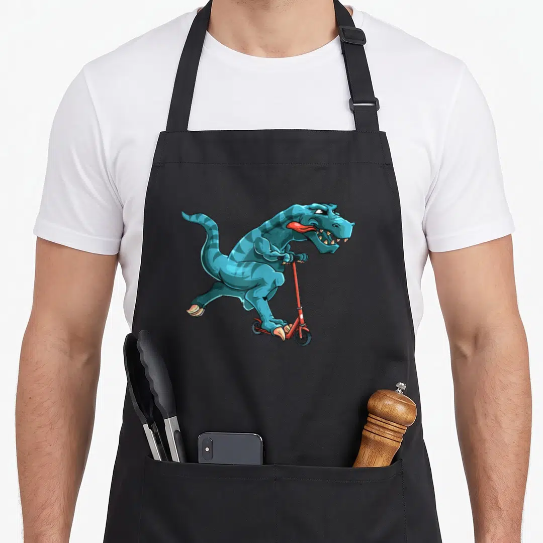 Dino scooter apron - Blue cartoon dinosaur riding a red scooter with grey background — shown on a black cotton canvas apron against a white background