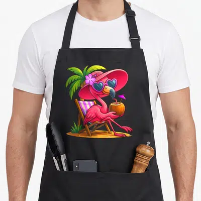 Vacation pink flamingo apron - Cartoon pink flamingo in beach chair with sunglasses, coconut drink, and palm tree — shown on a black cotton canvas apron against a white background