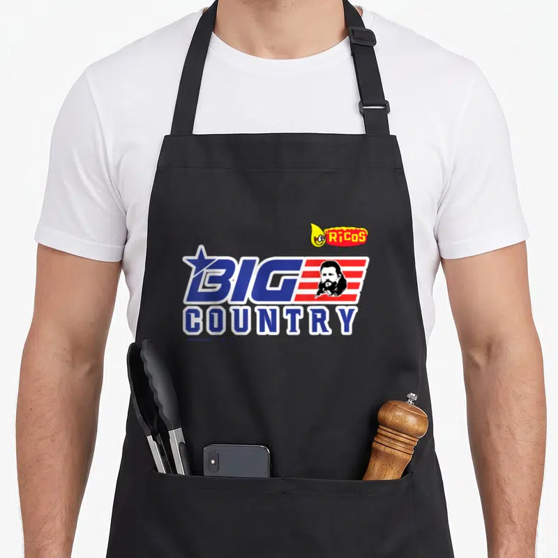Rico country apron - Big Country text with star stripes man face and Ricos mascot logo in blue white red yellow — shown on a black cotton canvas apron against a white background