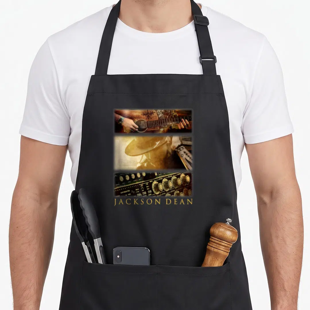 Jackson deans list apron - Three stacked photos of guitar, cowboy hat, and mixer with JACKSON DEAN text below — shown on a black cotton canvas apron against a white background