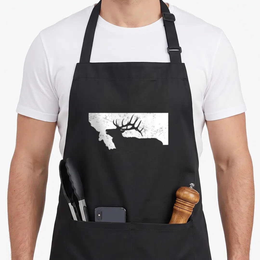 Hunting elk apron - White distressed Montana state shape containing a dark bull elk silhouette with antlers — shown on a black cotton canvas apron against a white background