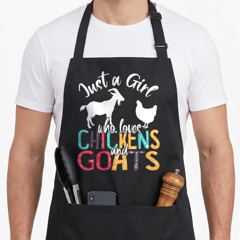 Chicken farmer apron - Just a Girl who loves CHICKENS and GOATS text with white goat and chicken silhouettes — shown on a black cotton canvas apron against a white background