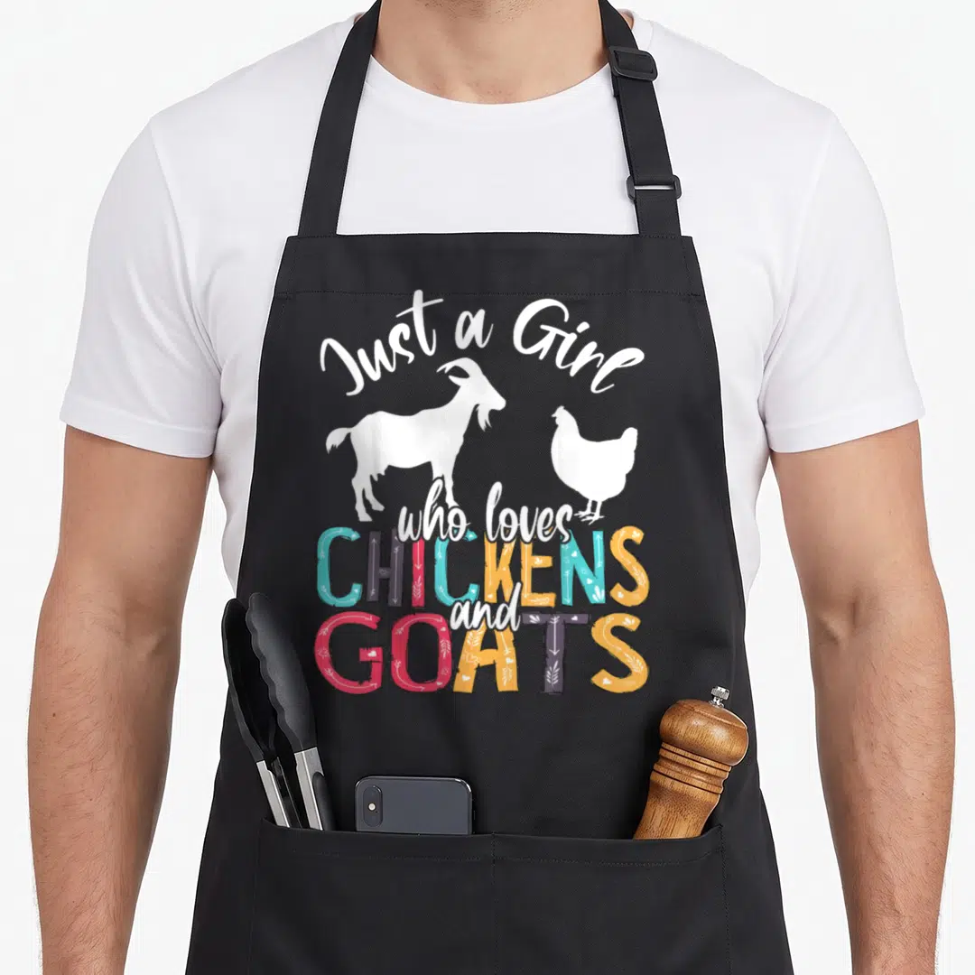 Chicken farmer apron - Just a Girl who loves CHICKENS and GOATS text with white goat and chicken silhouettes — shown on a black cotton canvas apron against a white background