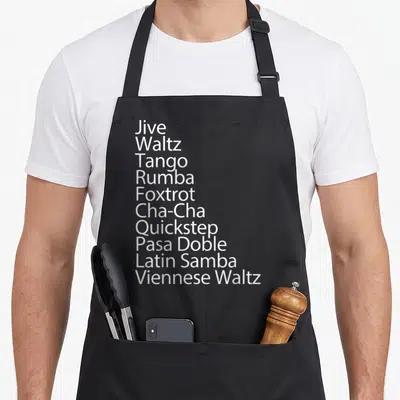 Ballroom traditional apron - White text listing Jive, Waltz, Tango, Rumba, Foxtrot, Cha-Cha, Quickstep, Pasa Doble — shown on a black cotton canvas apron against a white background