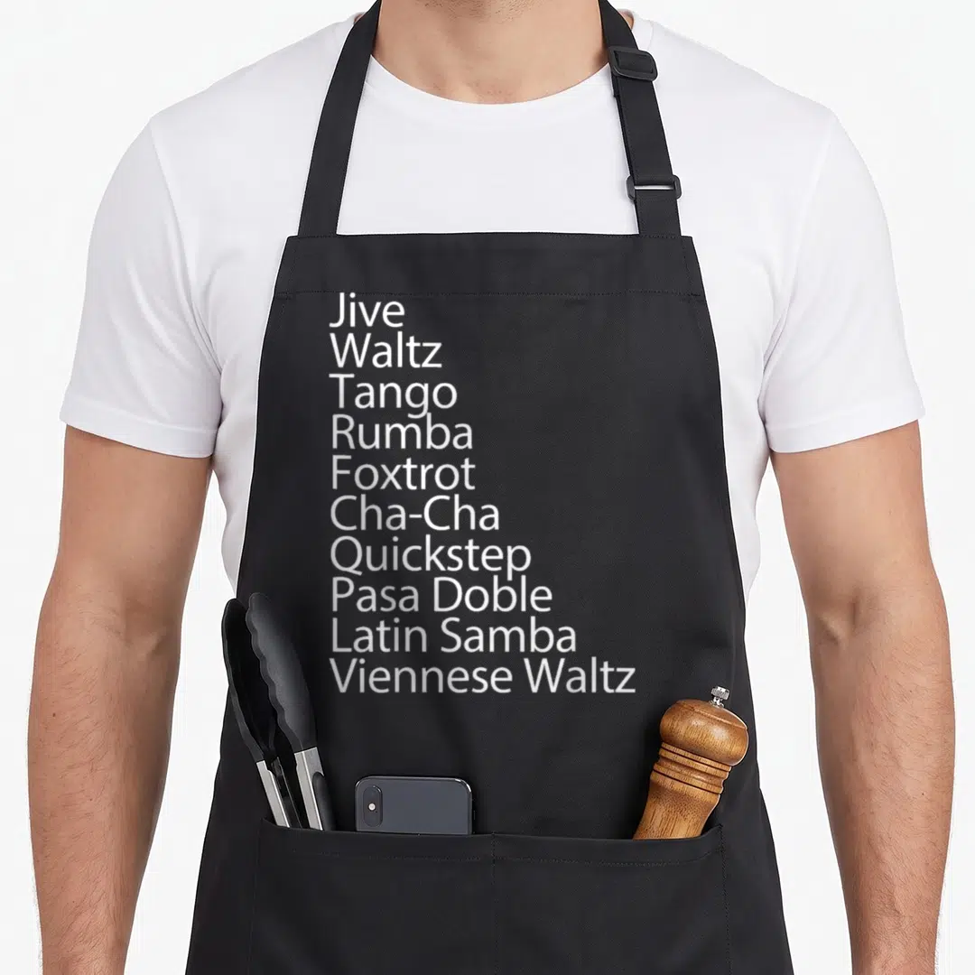 Ballroom traditional apron - White text listing Jive, Waltz, Tango, Rumba, Foxtrot, Cha-Cha, Quickstep, Pasa Doble — shown on a black cotton canvas apron against a white background