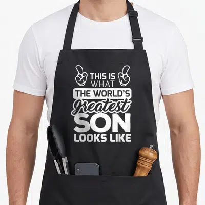 Son worlds greatest dad apron - White stacked text reading This Is What The Worlds Greatest Son Looks Like with two — shown on a black cotton canvas apron against a white background