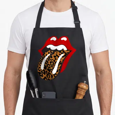 Rolling leopard apron - Cartoon mouth with red lips and leopard print tongue sticking out — shown on a black cotton canvas apron against a white background