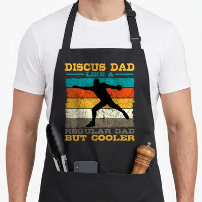 Discus father day apron - Black discus thrower silhouette over yellow blue orange grey stripes with retro text — shown on a black cotton canvas apron against a white background