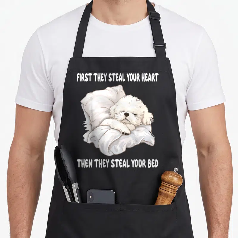 Nightdress bichon frise apron - Cartoon white dog sleeping on pillow with text first they steal your heart then they — shown on a black cotton canvas apron against a white background