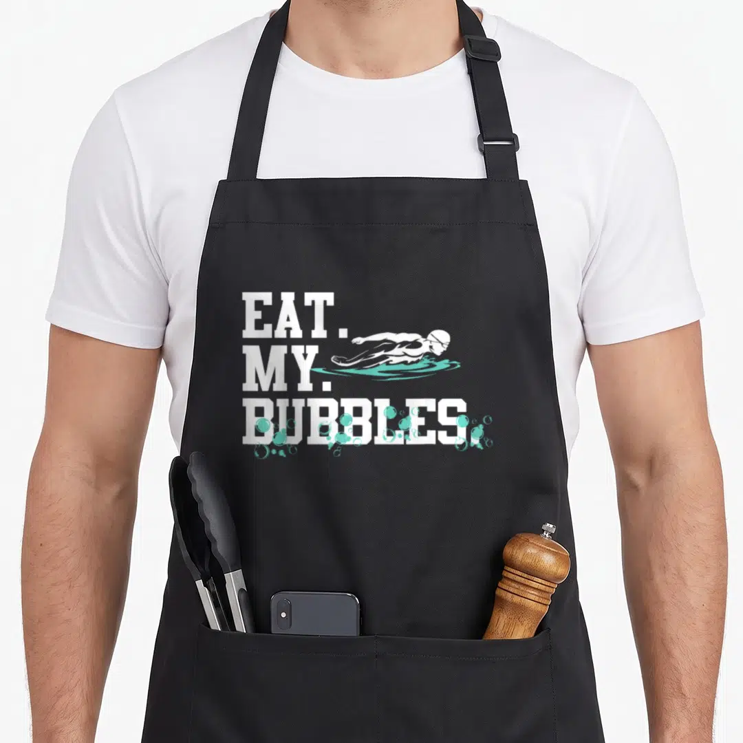 Bubble swimmer apron - EAT. MY. BUBBLES. text with white swimmer and teal bubbles — shown on a black cotton canvas apron against a white background