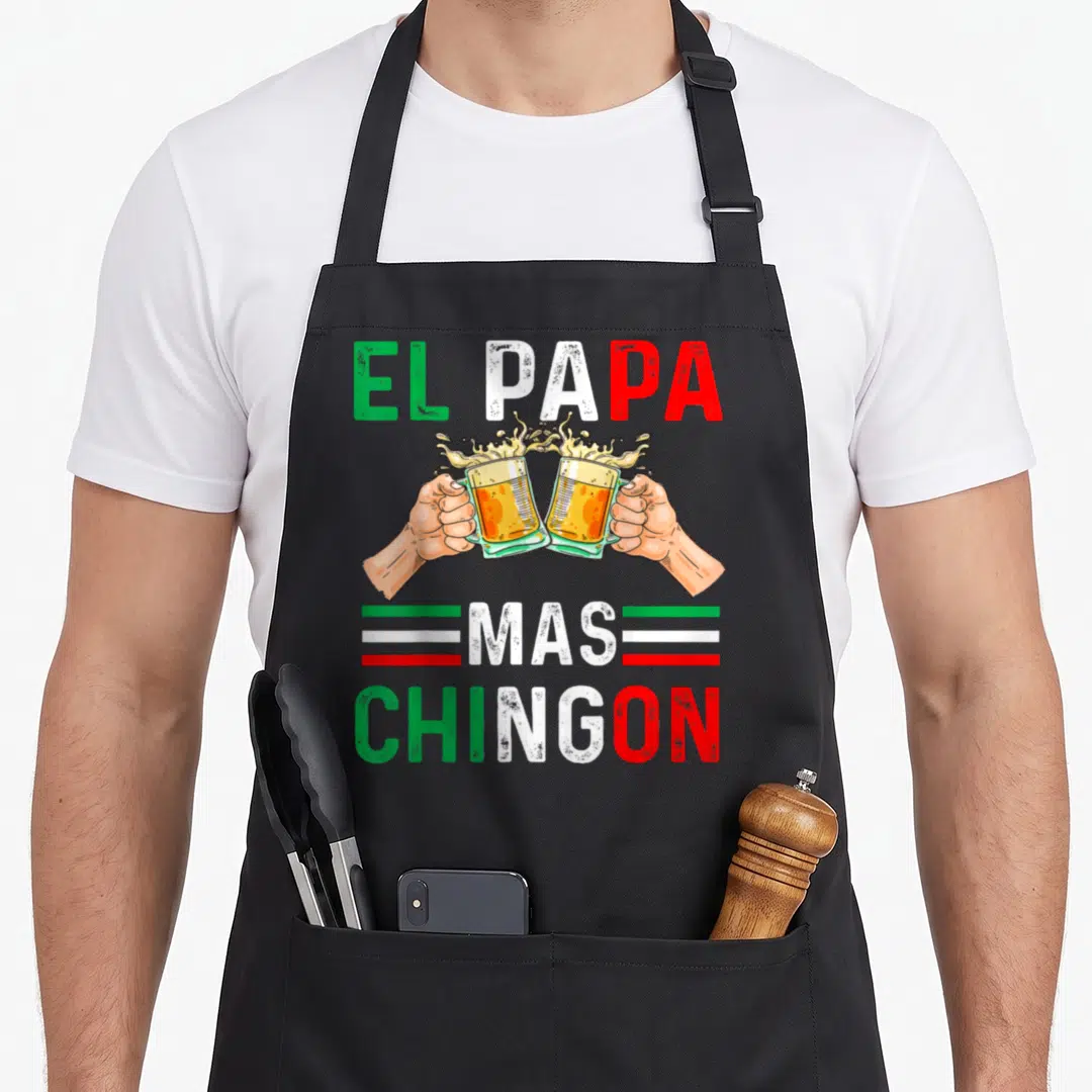 Chingon mexican apron - EL PAPA MAS CHINGON text with two clinking beer glasses and green white red stripes — shown on a black cotton canvas apron against a white background