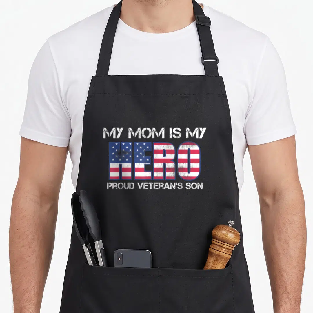 Military veteran family aprons - Distressed text MY MOM IS MY HERO with American flag pattern filling the center word — shown on a black cotton canvas apron against a white background
