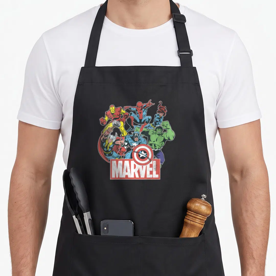 Funny comic novelty apron - Six superheroes in dynamic cartoon poses above a red box with white MARVEL text — shown on a black cotton canvas apron against a white background