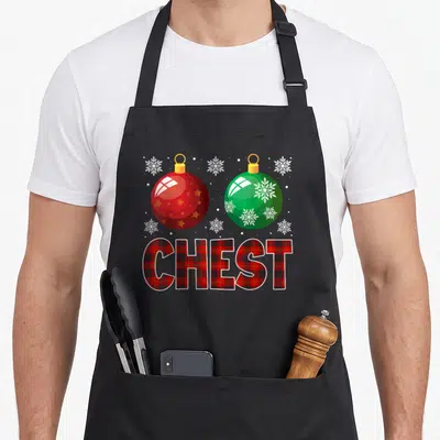 Nut couple family christmas aprons - Red and green Christmas ornaments above CHEST text in red plaid pattern surrounded — shown on a black cotton canvas apron against a white background