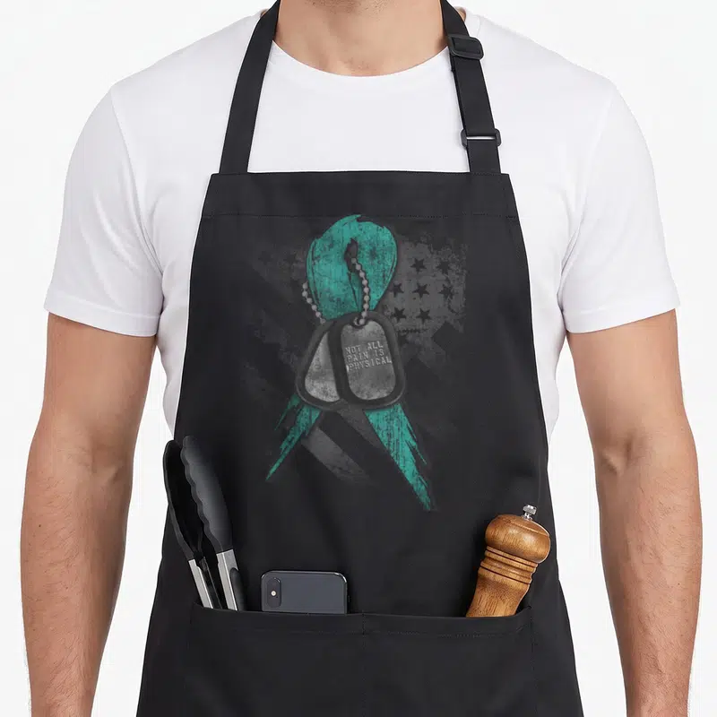 Pain ptsd awareness apron - Distressed teal ribbon behind two grey dog tags with engraved text — shown on a black cotton canvas apron against a white background
