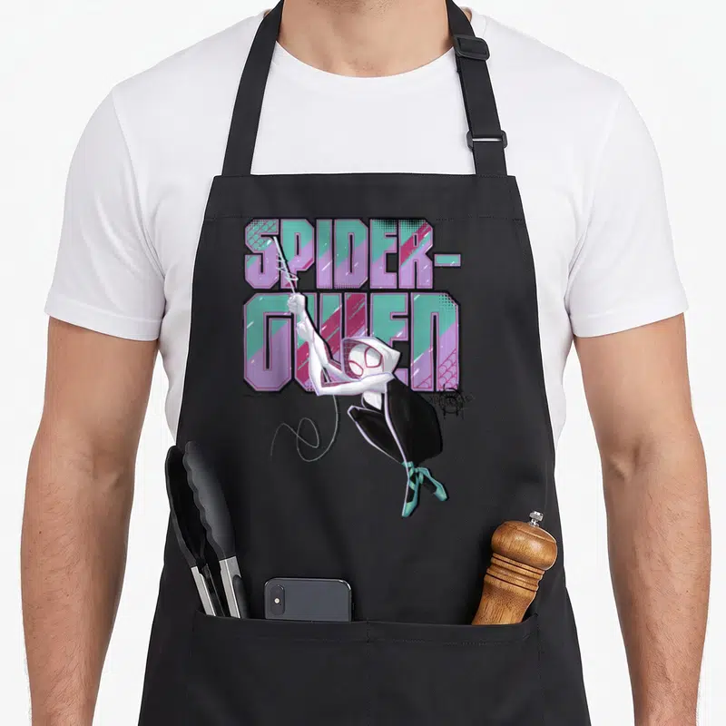 Spiderverse swing apron - Cartoon Spider-Gwen in white and black swinging in front of stacked purple and teal — shown on a black cotton canvas apron against a white background