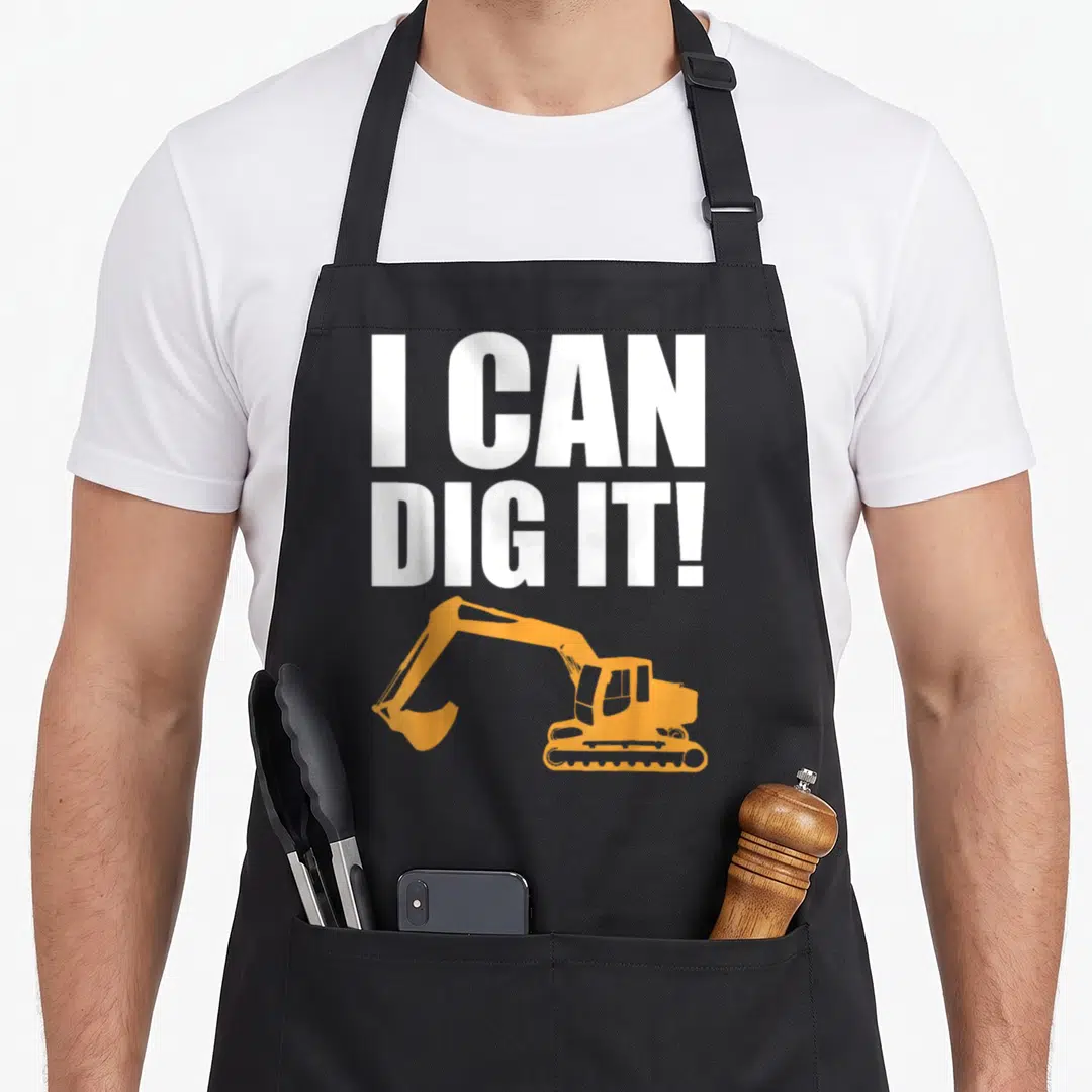 Landscaping construction apron - White I CAN DIG IT text above orange excavator silhouette — shown on a black cotton canvas apron against a white background