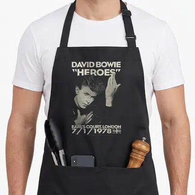 Earl david aprons - Halftone David Bowie portrait with Heroes text and Earl's Court 1978 date — shown on a black cotton canvas apron against a white background