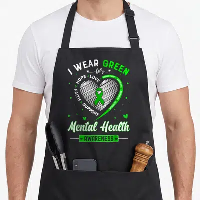 Month mental health awareness apron - White sketched heart with green ribbon and text I WEAR GREEN for HOPE LOVE FAMILY — shown on a black cotton canvas apron against a white background