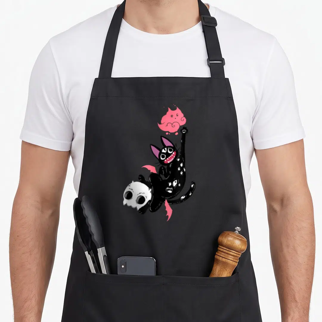 Kawaii black cat apron - Floating black cat with pink wings holding white skull reaching for pink ghost — shown on a black cotton canvas apron against a white background