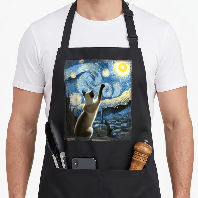 Gogh cute cat aprons - Cat seen from behind reaching up at swirling blue yellow cream starry night sky — shown on a black cotton canvas apron against a white background