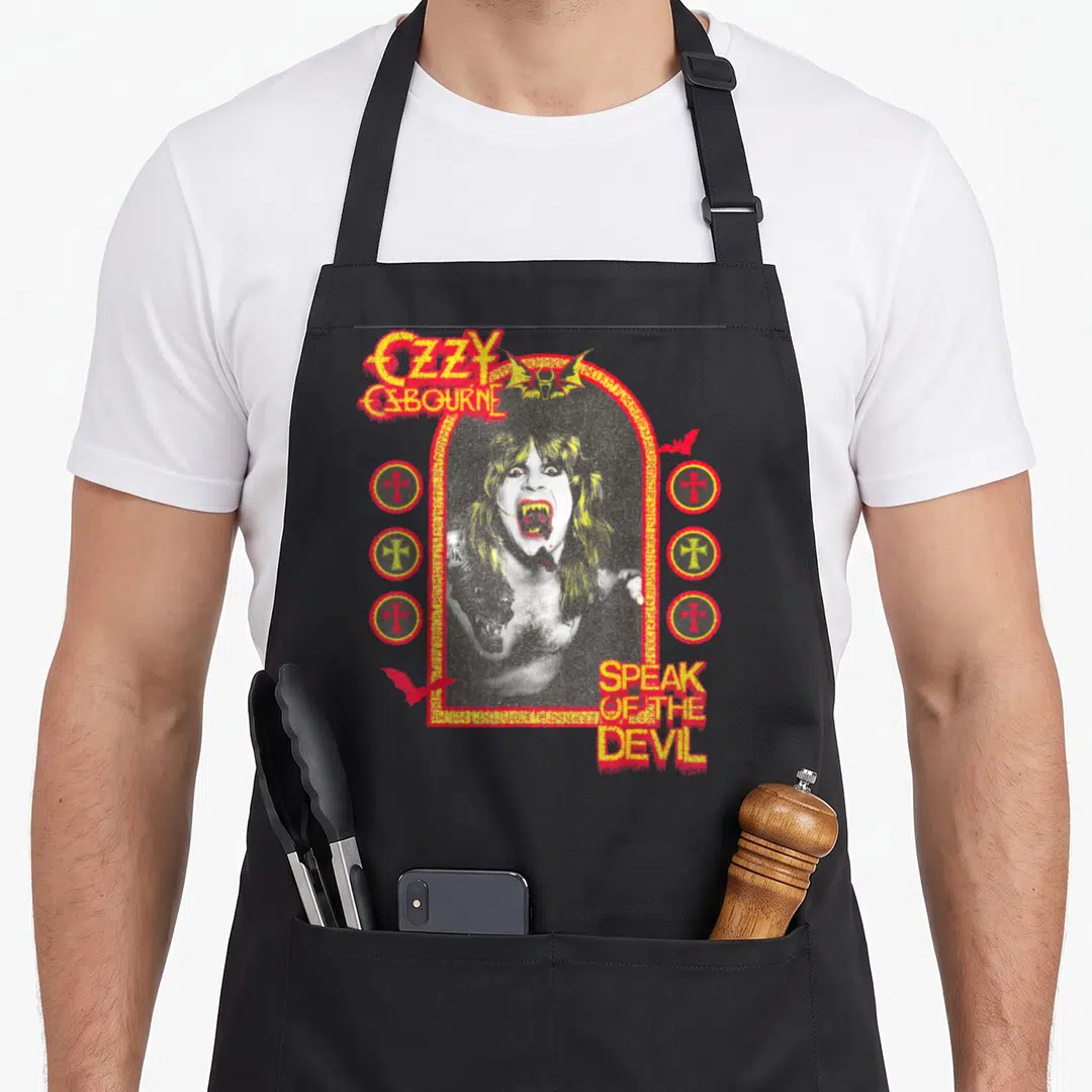 Osbourne devil's apron - Distressed red and yellow OZZY OSBOURNE SPEAK OF THE DEVIL text surrounding a central photo — shown on a black cotton canvas apron against a white background