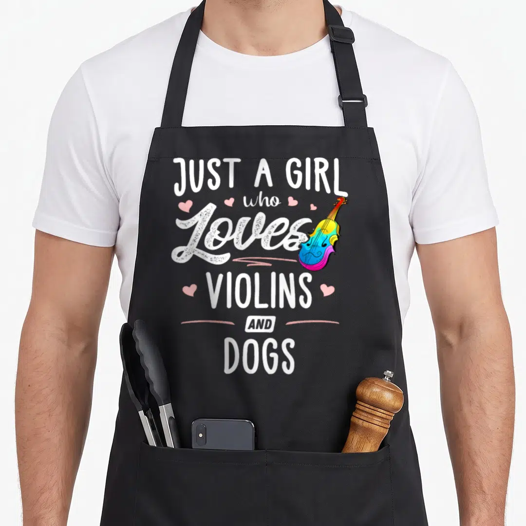 Violin dog apron - Stacked white text Just A Girl Who Loves Violins And Dogs with rainbow violin and pink hearts — shown on a black cotton canvas apron against a white background